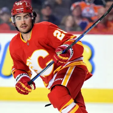 Hockey player in red Calgary Flames uniform skating on ice.