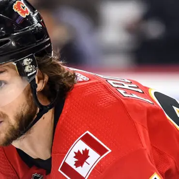 Ice hockey player in red Canadian jersey focused on the game.