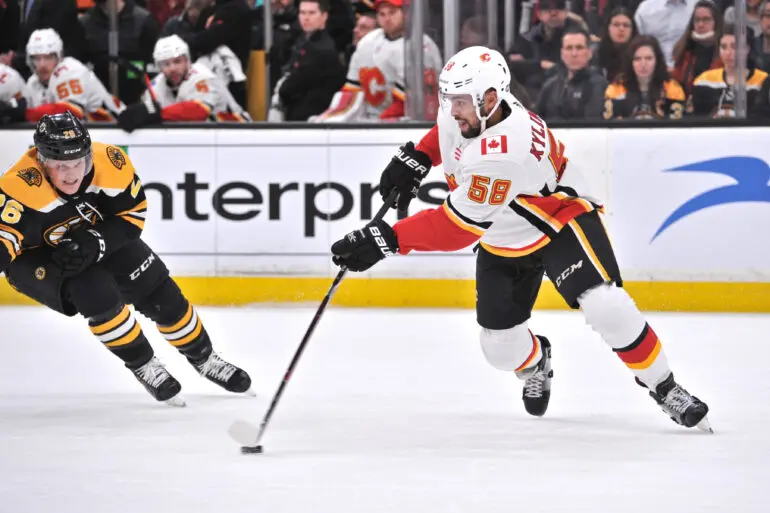 Two hockey players competing during a game, one in a white jersey and the other in black.
