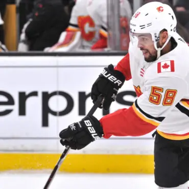 Hockey player in white and red jersey skating with the puck during a game.