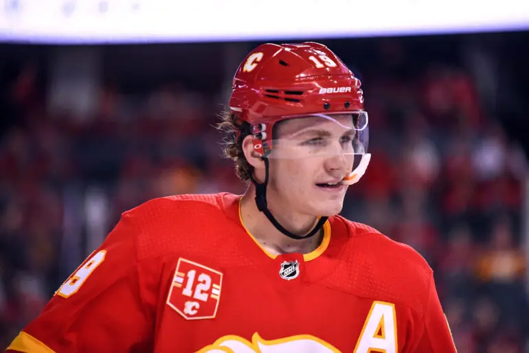 Hockey player in red jersey with an 'A' on it, wearing a helmet.