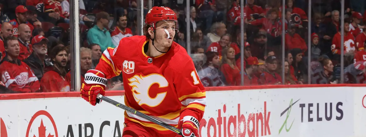 Hockey player in red Calgary Flames jersey on ice during a game.
