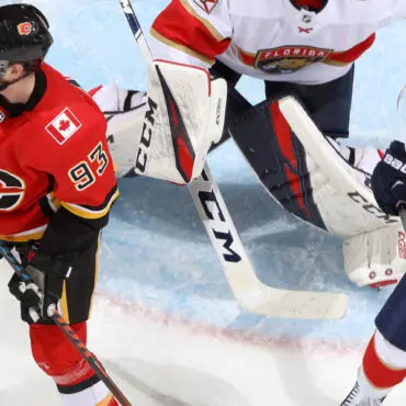 Two ice hockey players in action near the goal crease.