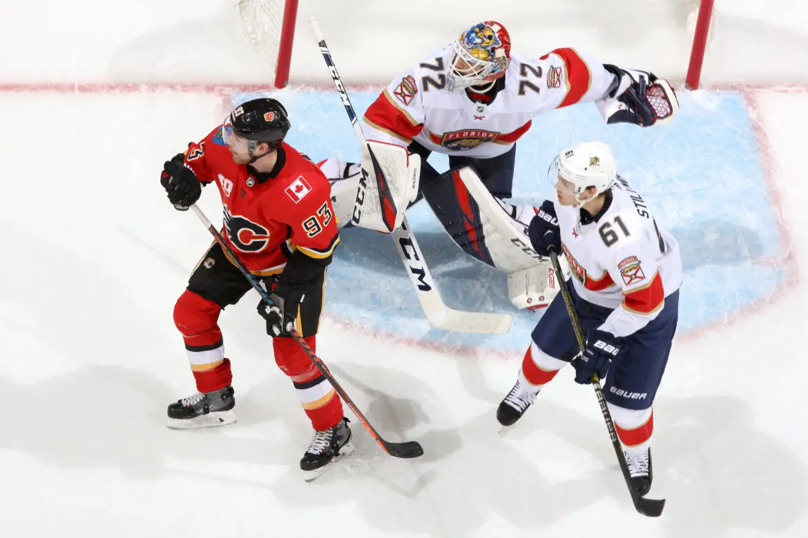 Ice hockey players compete intensely near the goal with goalie ready to defend.