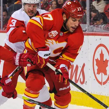 Two hockey players competing aggressively on the ice rink.