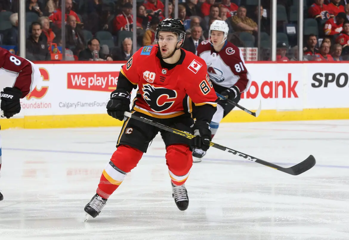 Ice hockey player in red and black jersey skating on the rink.