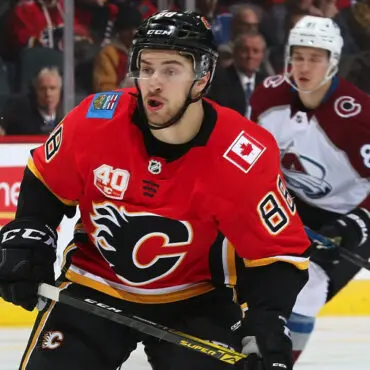 Hockey player in red Calgary Flames jersey skating on ice.