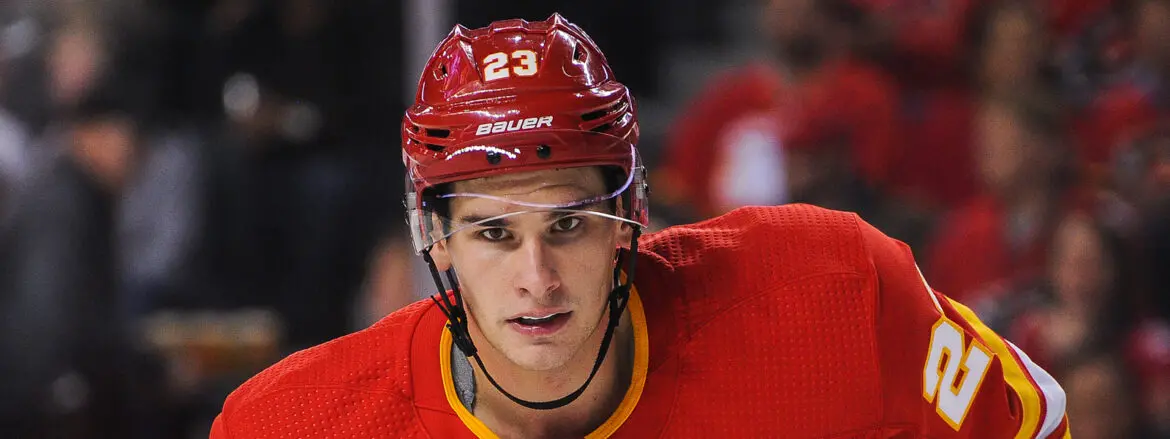 Close-up of a focused hockey player in a red helmet and jersey.