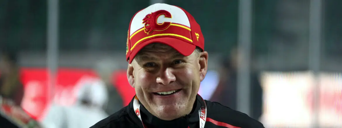 Smiling man wearing a Calgary Flames cap and jacket.