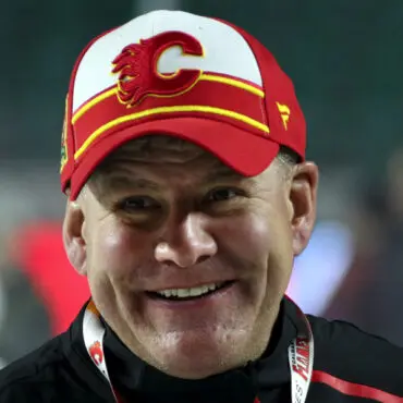 Smiling man wearing a Calgary Flames cap and jacket.