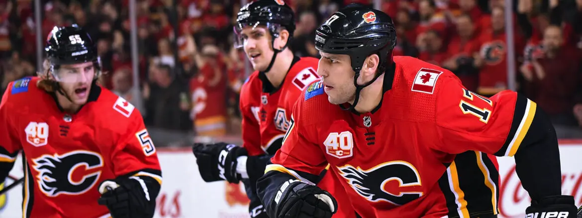 Two hockey players in red jerseys on the bench during a game.