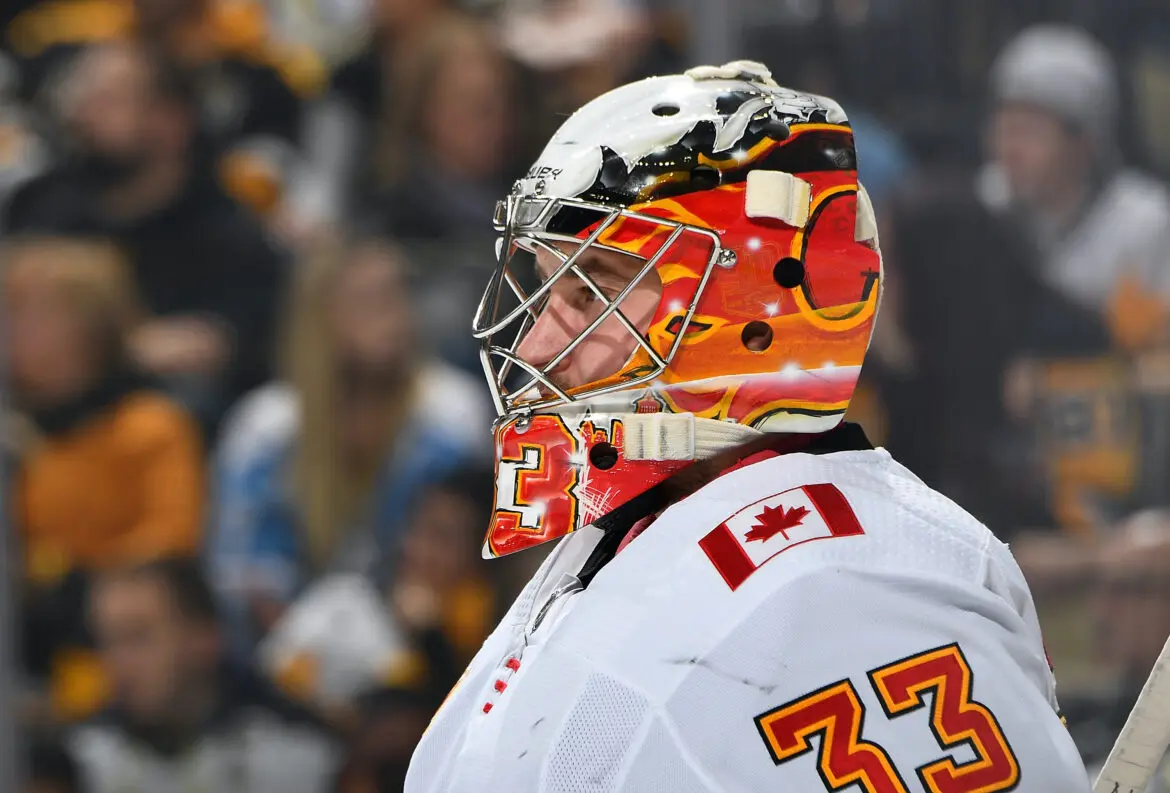Ice hockey goalie in action wearing a colorful mask and Canadian jersey.