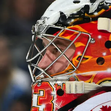 Close-up of a hockey goalie in a fiery-themed mask.