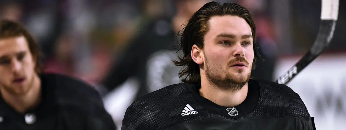 Close-up of a hockey player in black Adidas gear during a game.