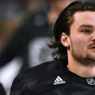 Close-up of a hockey player in black Adidas gear during a game.