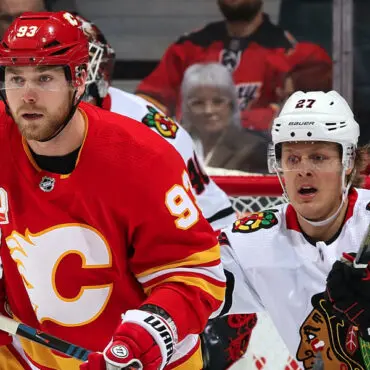 Two NHL players from Calgary Flames and Chicago Blackhawks in action during a game.