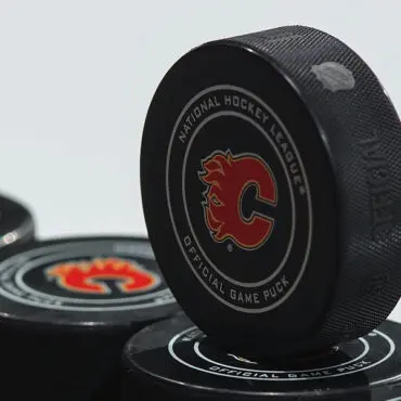 Hockey pucks stacked, featuring Calgary Flames logos.