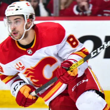 Hockey player in red and white uniform skating on ice.
