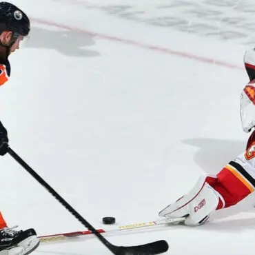 Two ice hockey players competing for the puck on the rink.