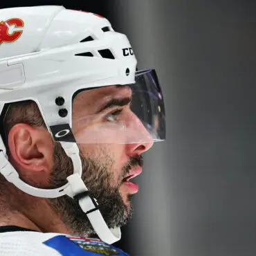 Profile of a focused ice hockey player wearing a white helmet.