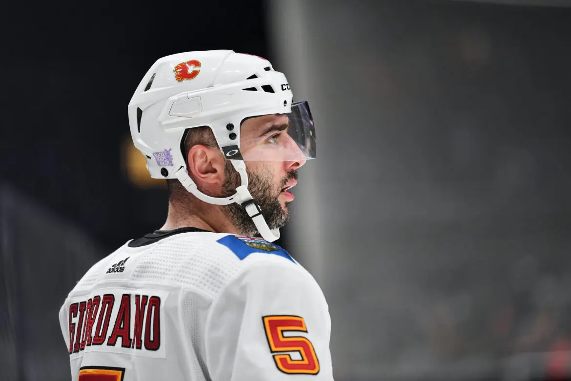 A hockey player in white gear and helmet focused on the game.
