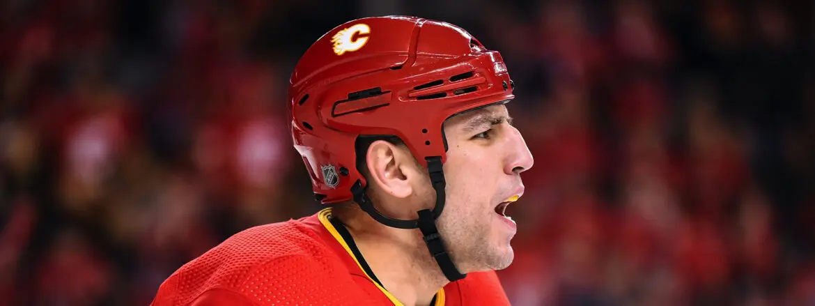 Hockey player in red Calgary Flames helmet focused during a game.