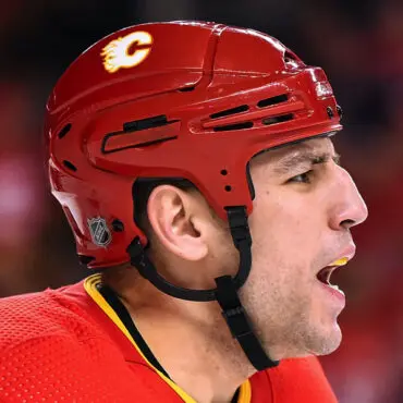 Hockey player in red Calgary Flames helmet focused during a game.