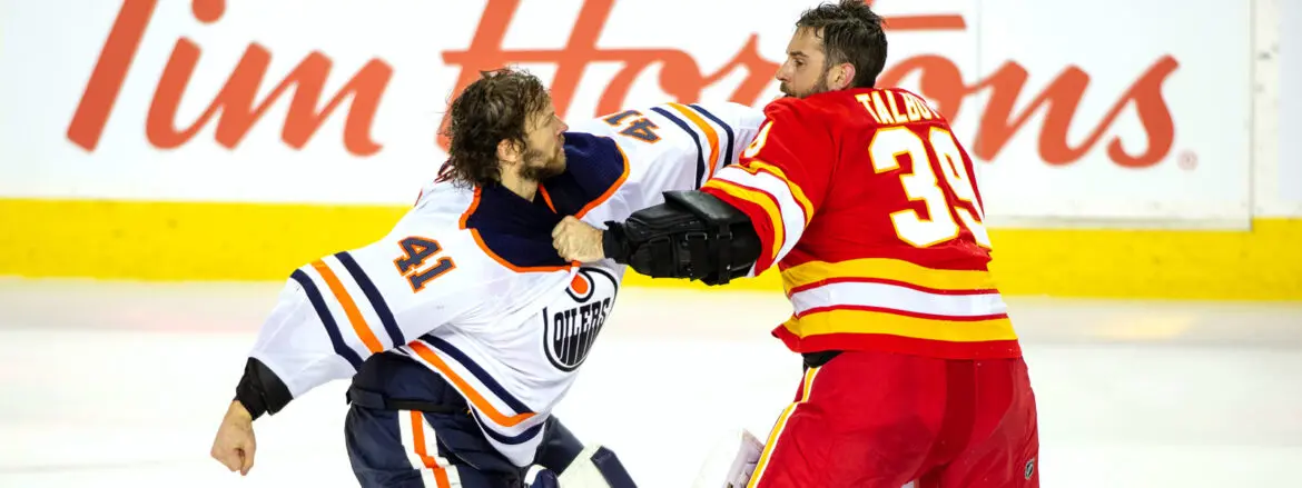 Two hockey players fighting on the ice during a game.
