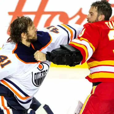 Two hockey players fighting on the ice during a game.