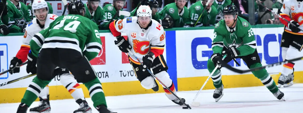 Hockey player in white and red jersey skating with puck on ice rink.