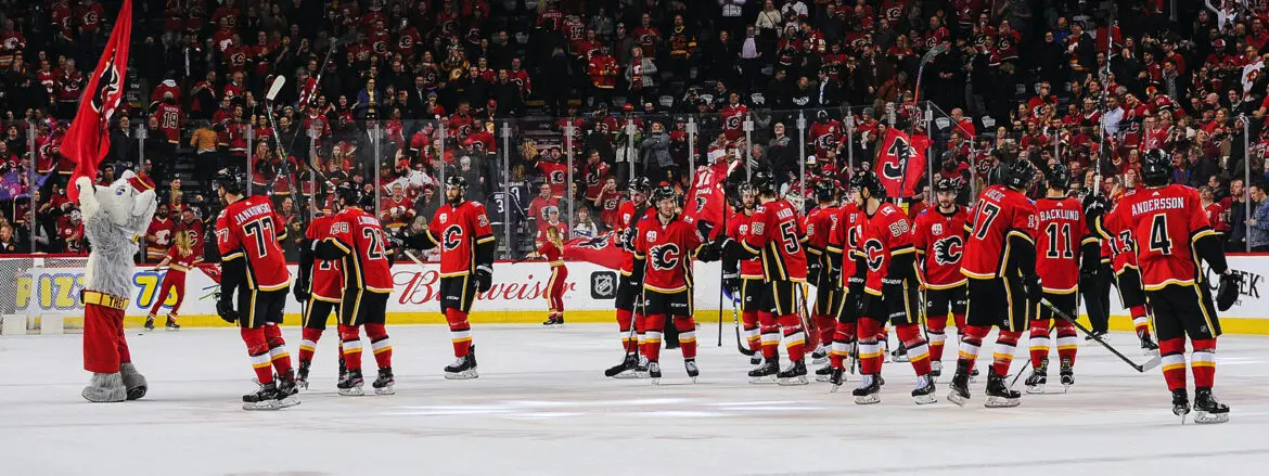 Hockey players celebrating on ice in red jerseys.