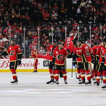 Hockey players celebrating on ice in red jerseys.