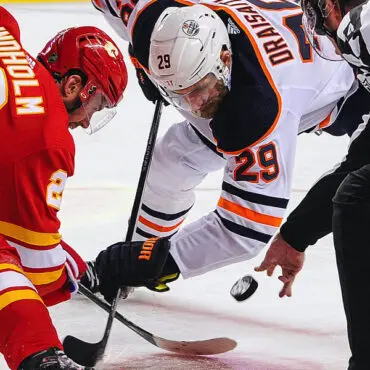 Two hockey players face off for the puck during a game.