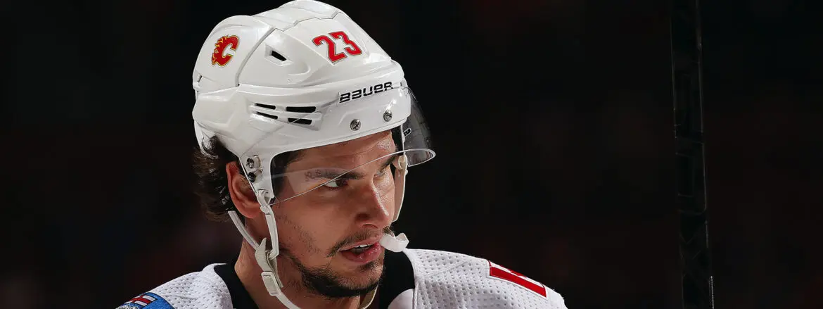 Close-up of a hockey player in a white helmet with number 23.