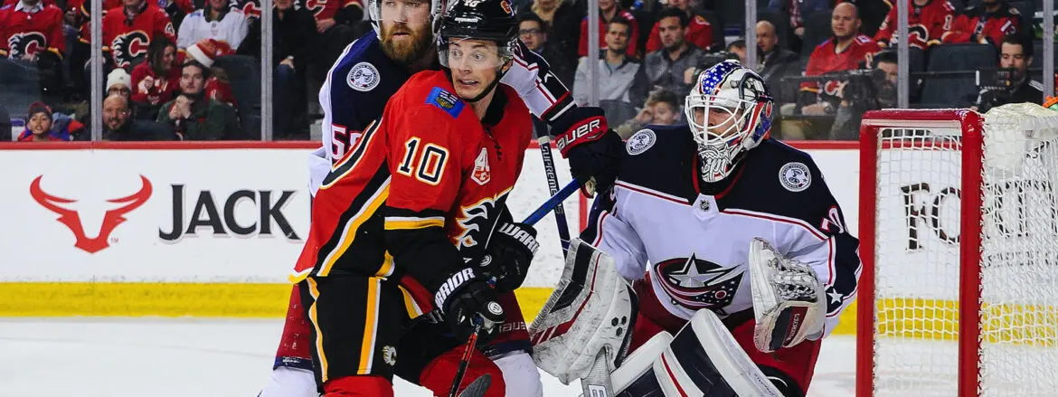 Hockey players from Calgary Flames and Columbus Blue Jackets in action near the goal.