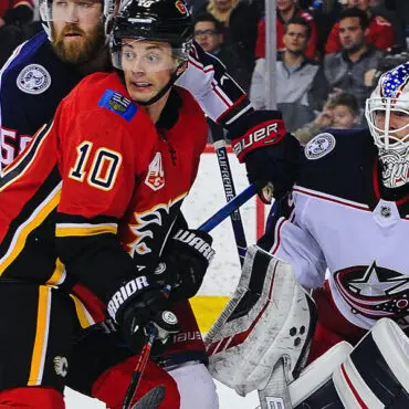 Hockey players from Calgary Flames and Columbus Blue Jackets in action near the goal.