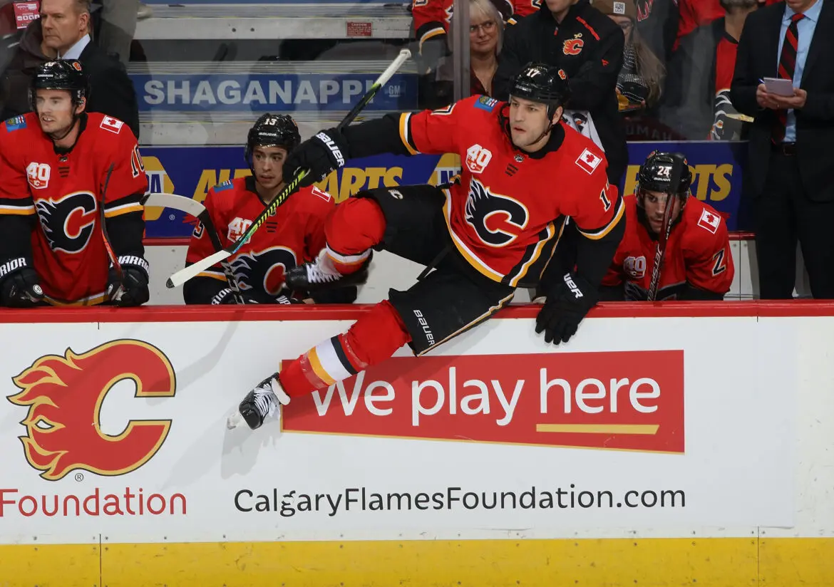 Calgary Flames hockey player jumping over the boards during a game.