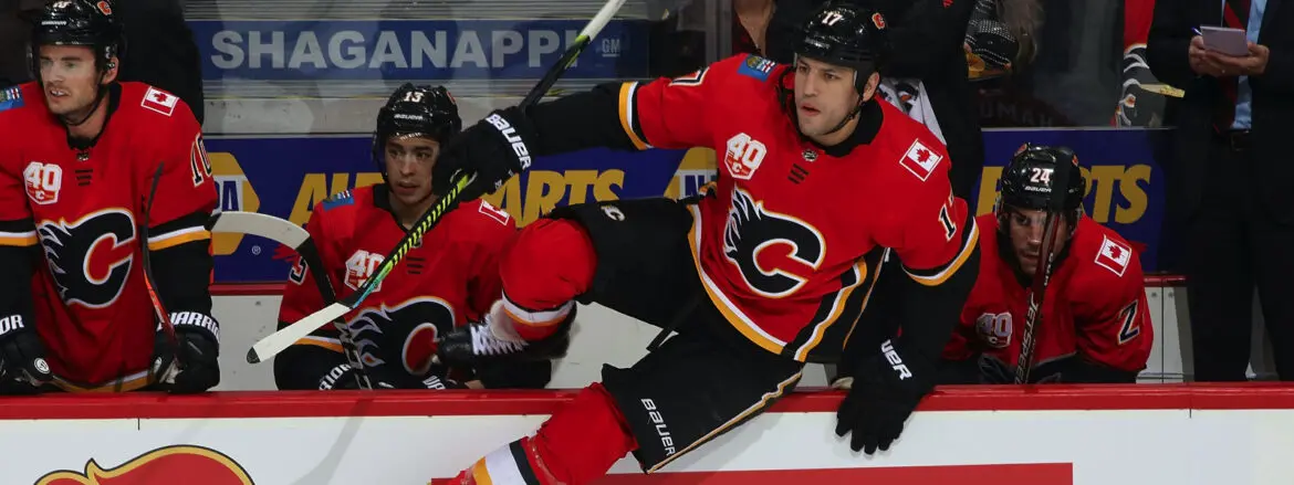 Two hockey players in red Calgary Flames jerseys in action on the ice.