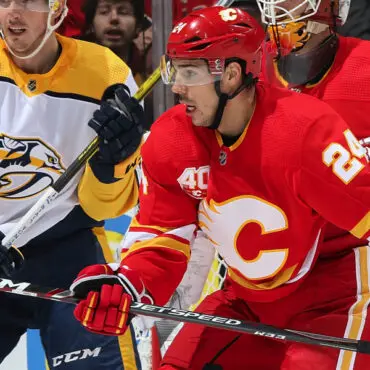 Hockey players from Calgary Flames and Nashville Predators compete intensely on the ice.