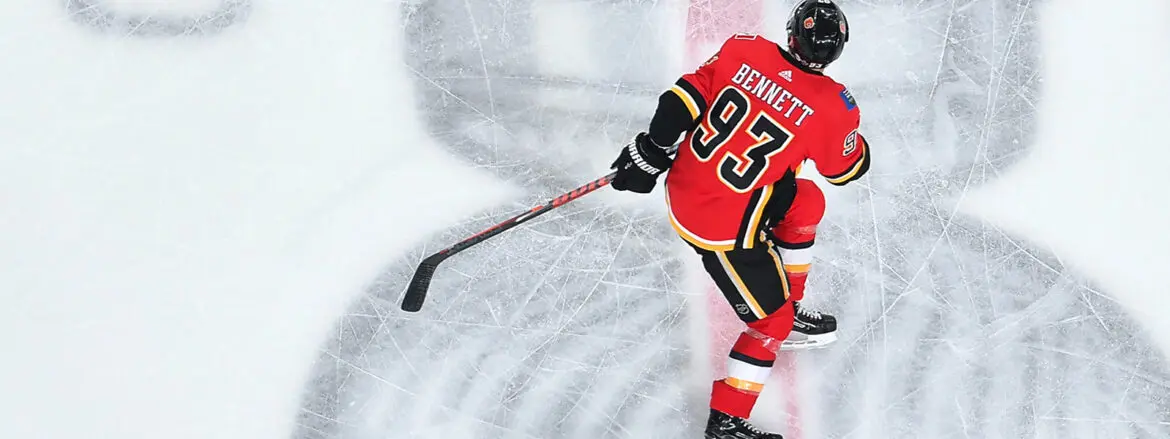 Hockey player in red and yellow jersey skating on ice with puck.