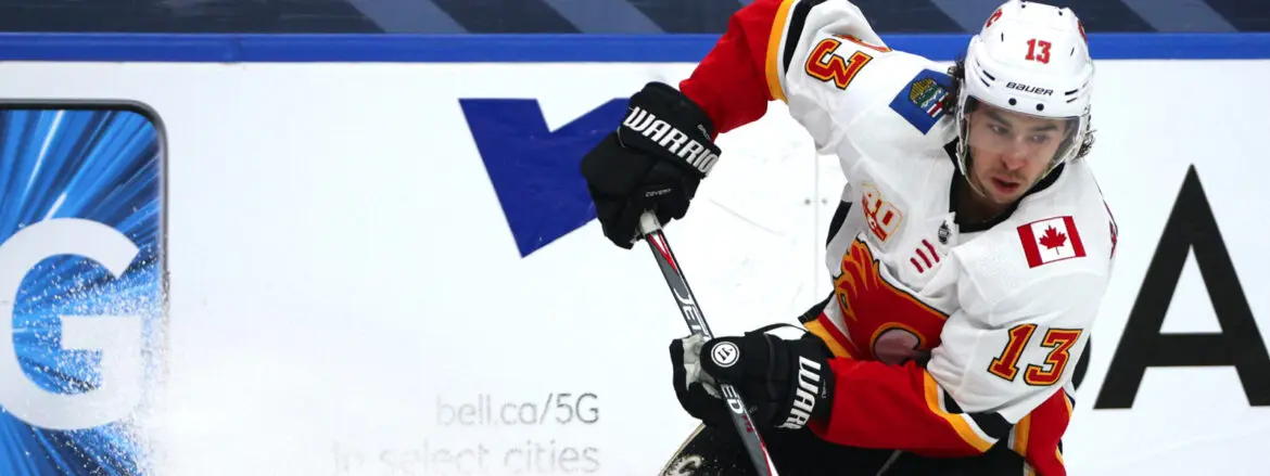 Hockey player in red and white gear controls the puck with a stick on ice.
