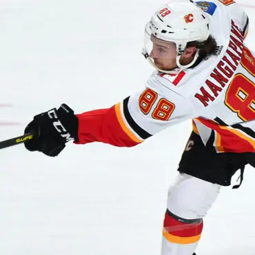 Hockey player in white and red jersey taking a shot on ice.