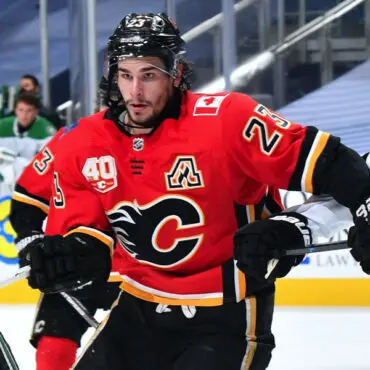 Hockey player in a red Calgary Flames jersey skating on ice.
