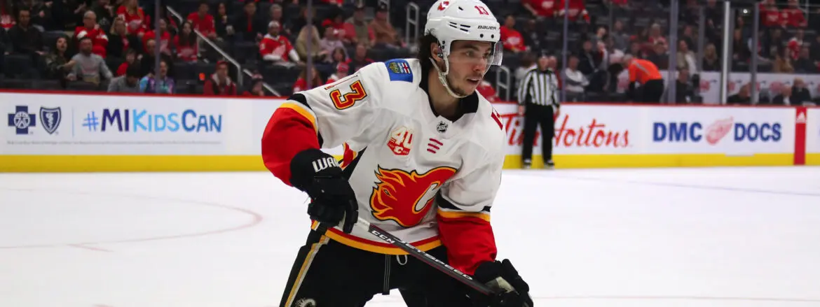 A hockey player in a white and red Calgary Flames jersey on ice.