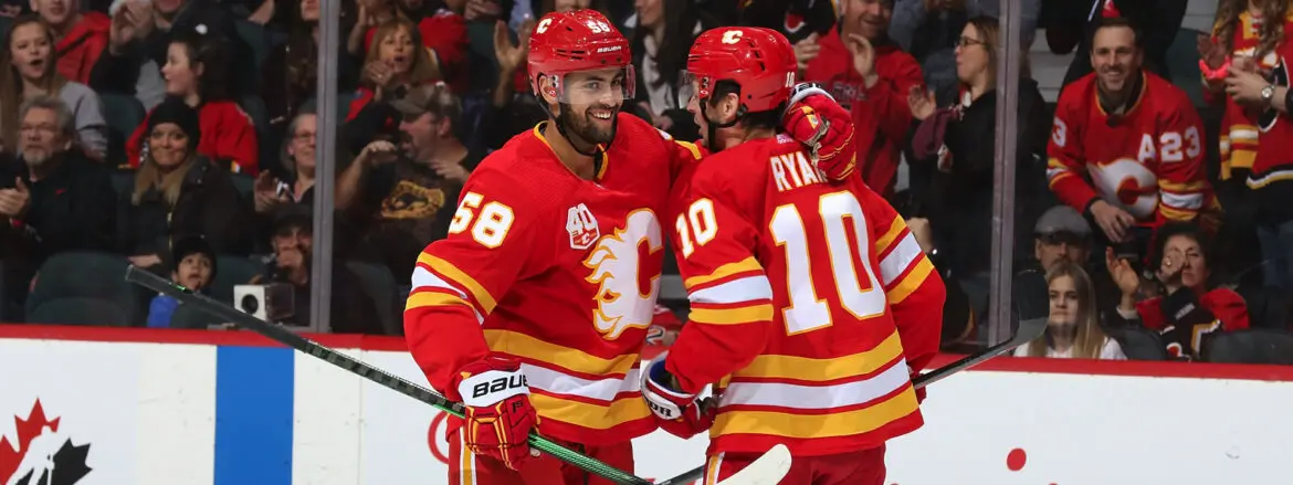 Two Calgary Flames players in red and yellow uniforms during a hockey game.