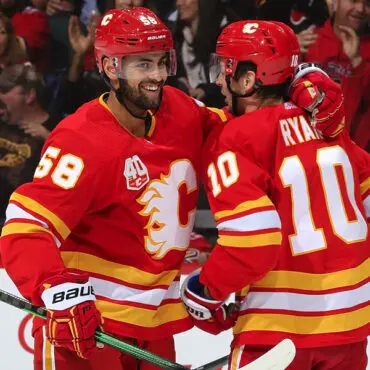 Two Calgary Flames players in red and yellow uniforms during a hockey game.