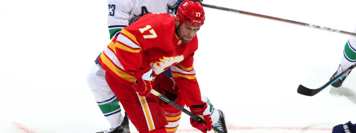 Hockey player in red jersey controlling the puck.