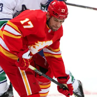 Hockey player in red jersey controlling the puck.