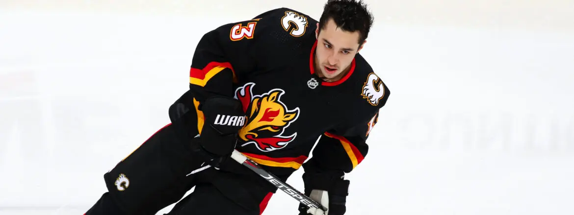 Hockey player in black Calgary Flames jersey skating intensely.