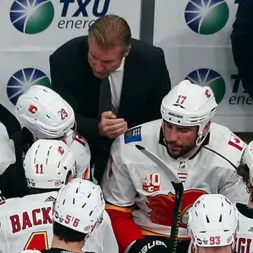 Hockey coach strategizing with players during a timeout.